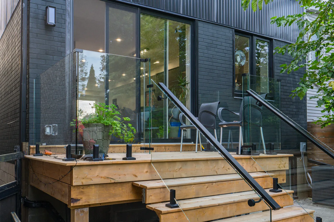 Rear deck landing and stairs with frameless glass railing against a dark-clad home in Ajax
