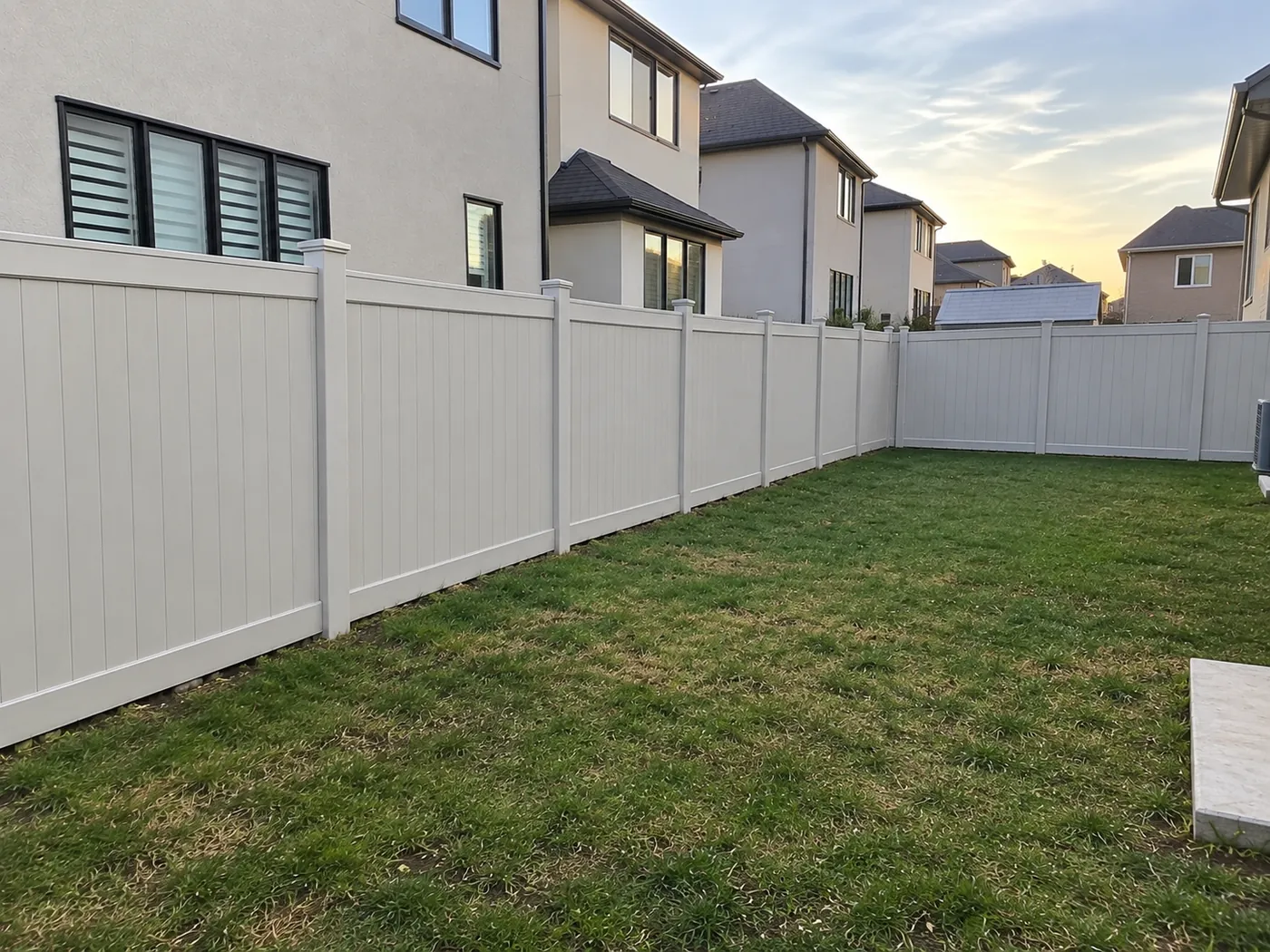 Off-white vinyl privacy fence turning the corner of a Milton backyard