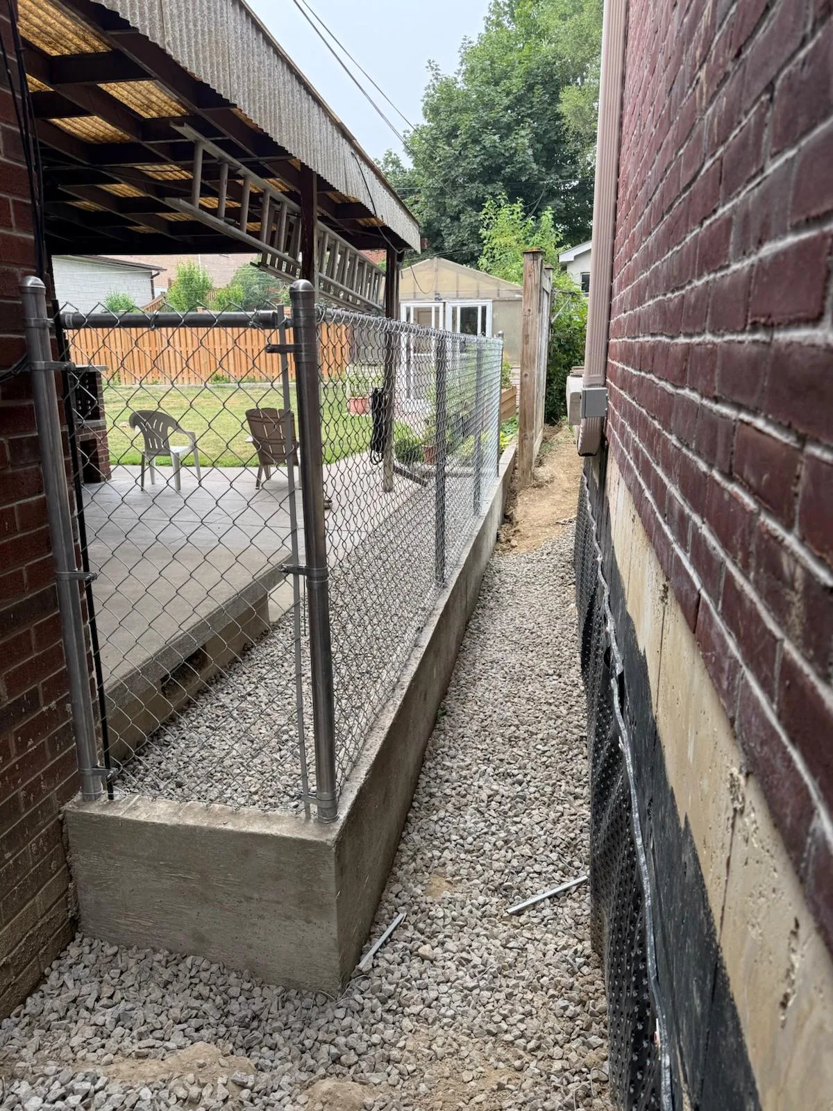 Galvanized chain link fence set on a poured concrete base in a Mississauga side yard