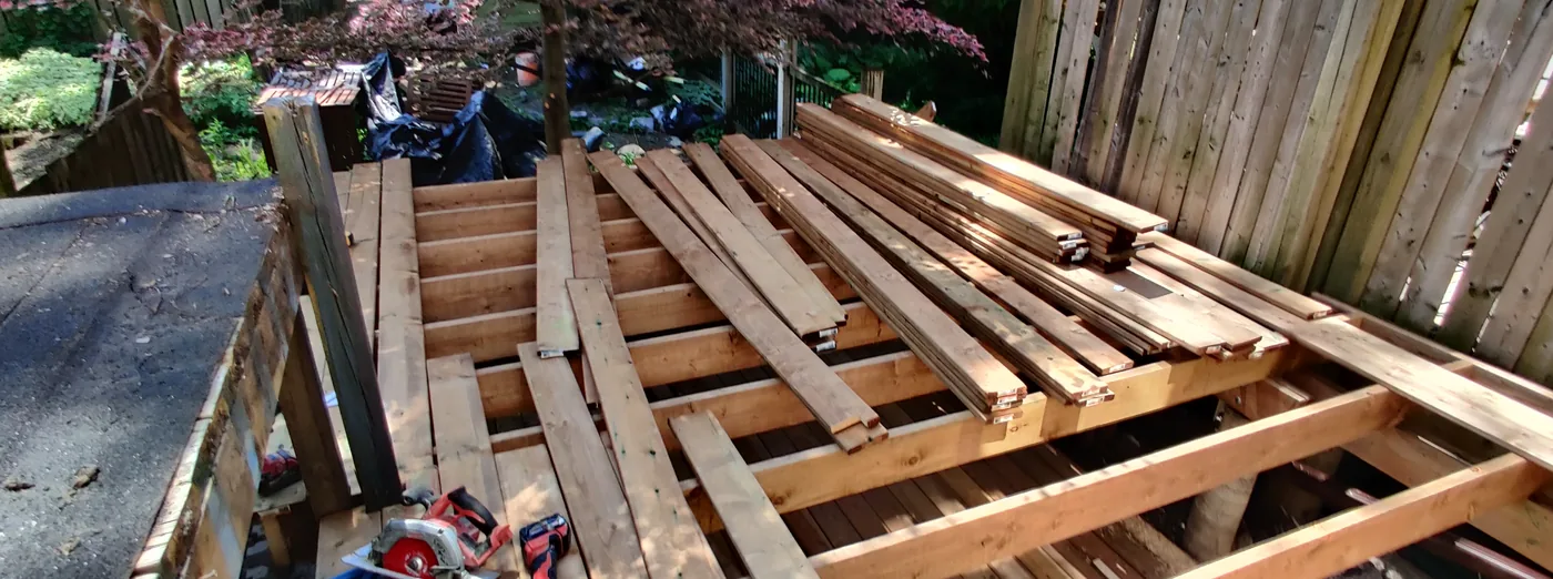 Pressure-treated deck boards going down over the new joists in North York