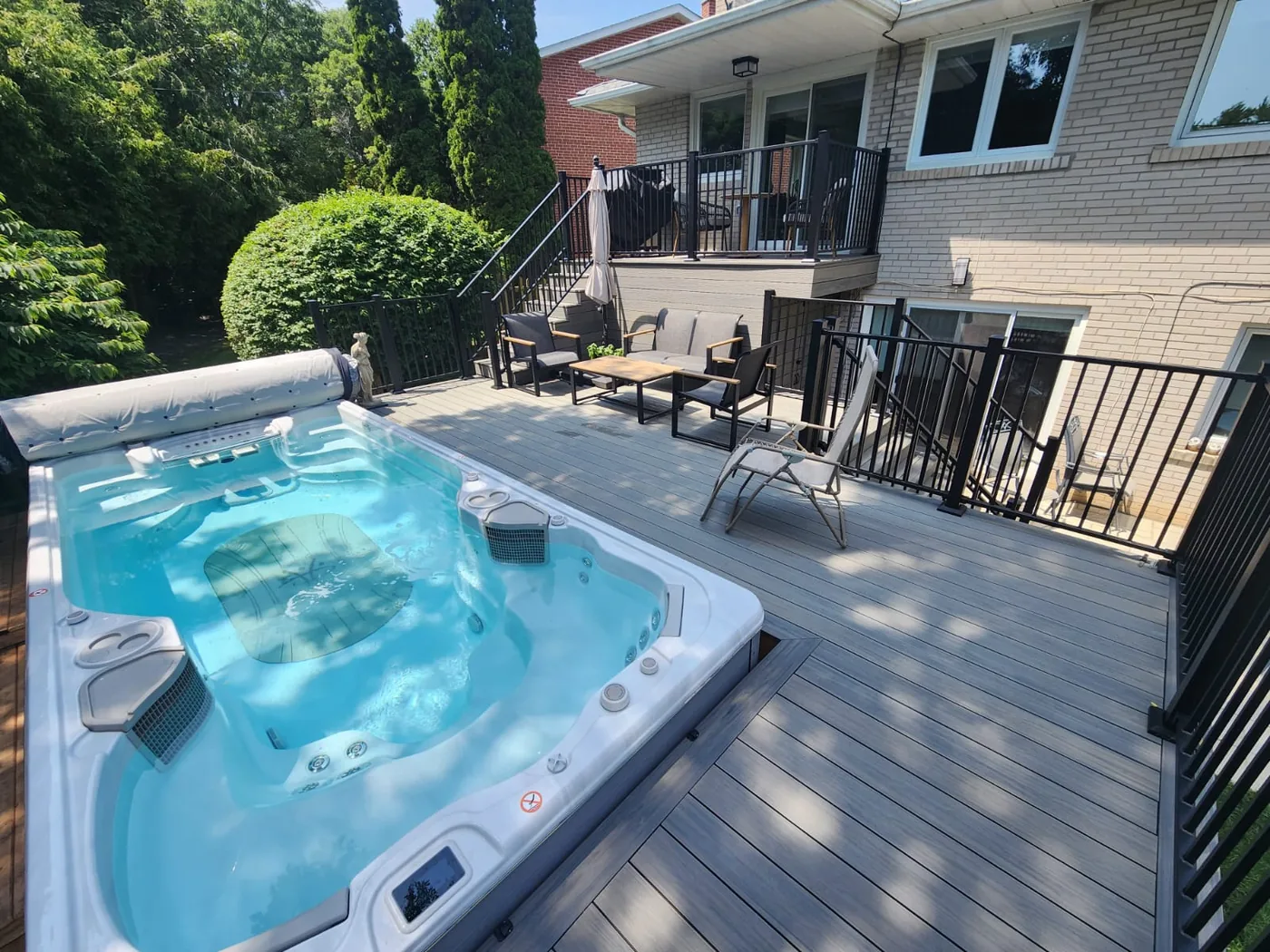 Swim spa set into a composite deck with black aluminum railings in North York
