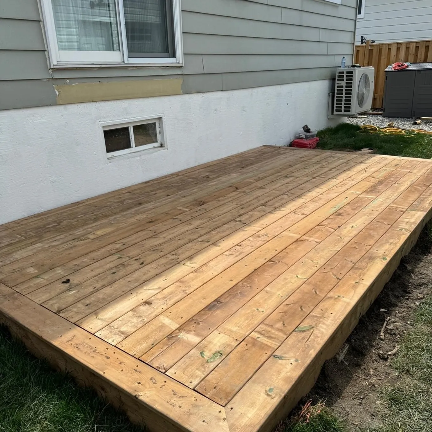 Freestanding pressure-treated deck sitting just above grade against the house, Pickering