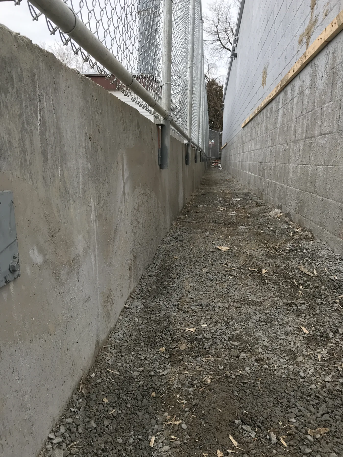 The narrow gap between buildings closed off with chain link on the existing concrete wall, Scarborough