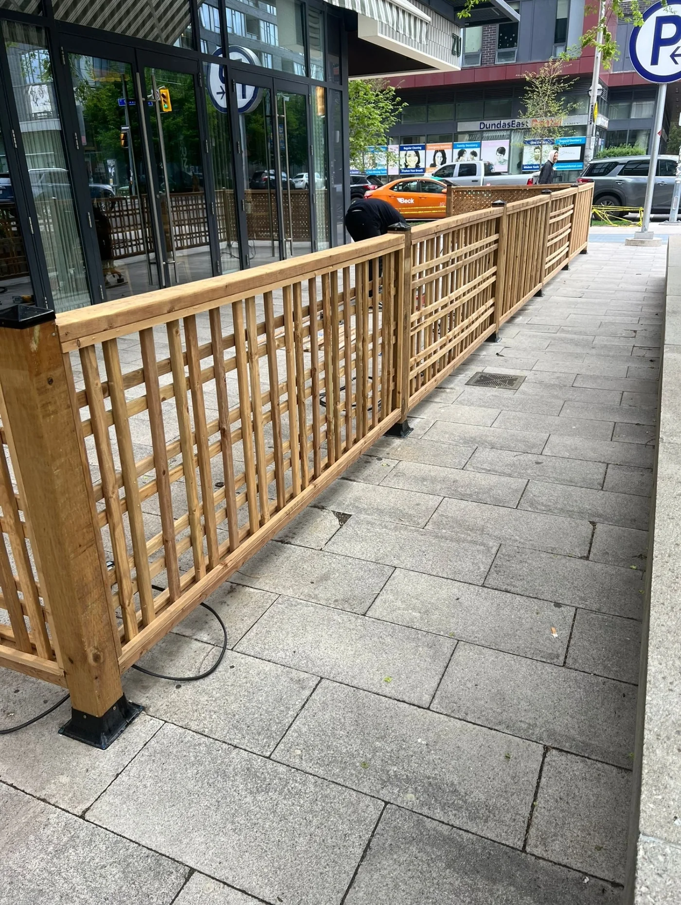 Long run of pressure-treated lattice screen enclosing a restaurant patio on a Toronto sidewalk