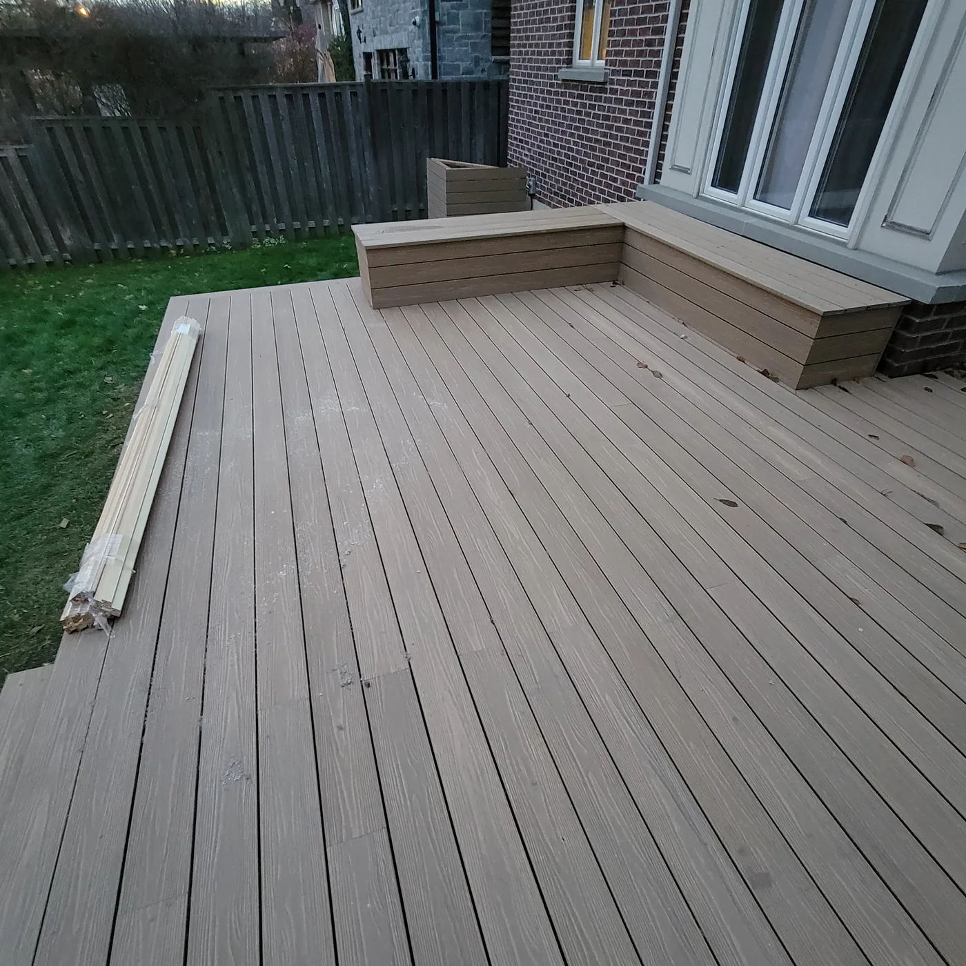 Composite deck boards running to a built-in bench under a bay window in Toronto