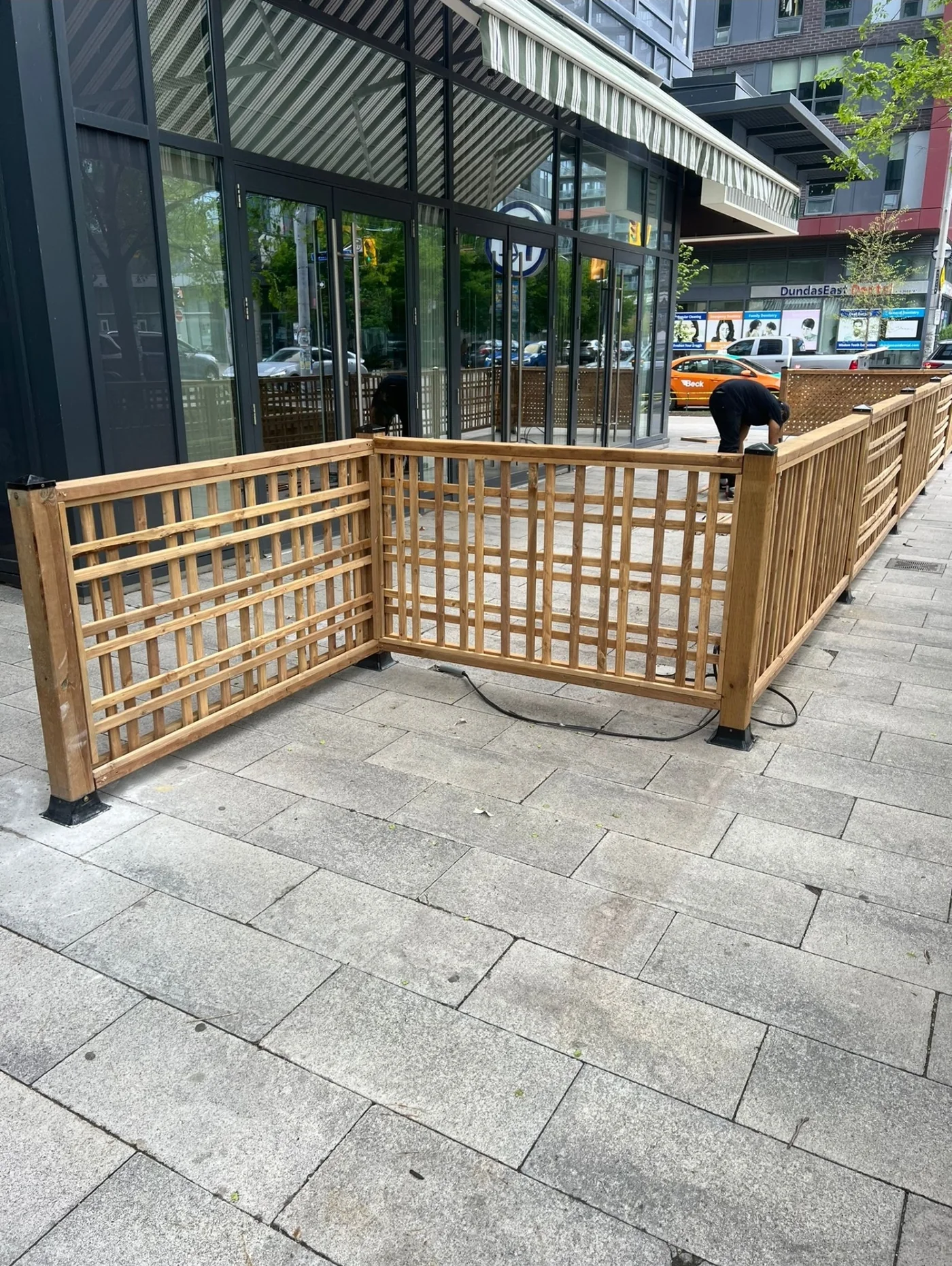 Patio screen panels being set on their base plates on the sidewalk in Toronto