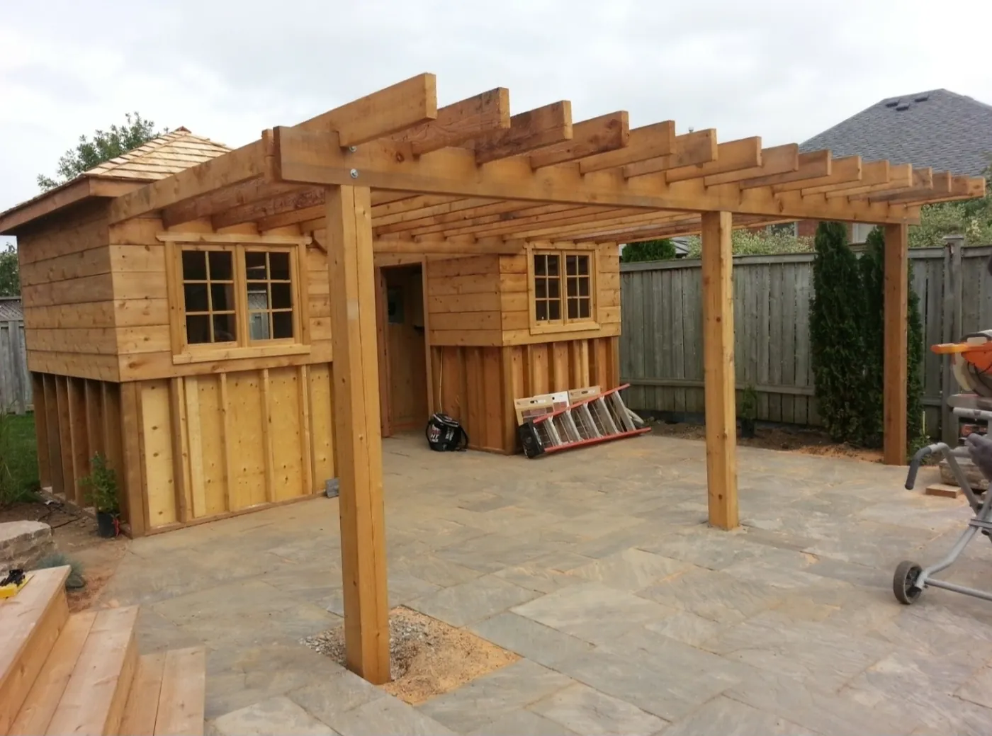 Pergola carried off a cedar storage shed over a flagstone patio in a Toronto backyard